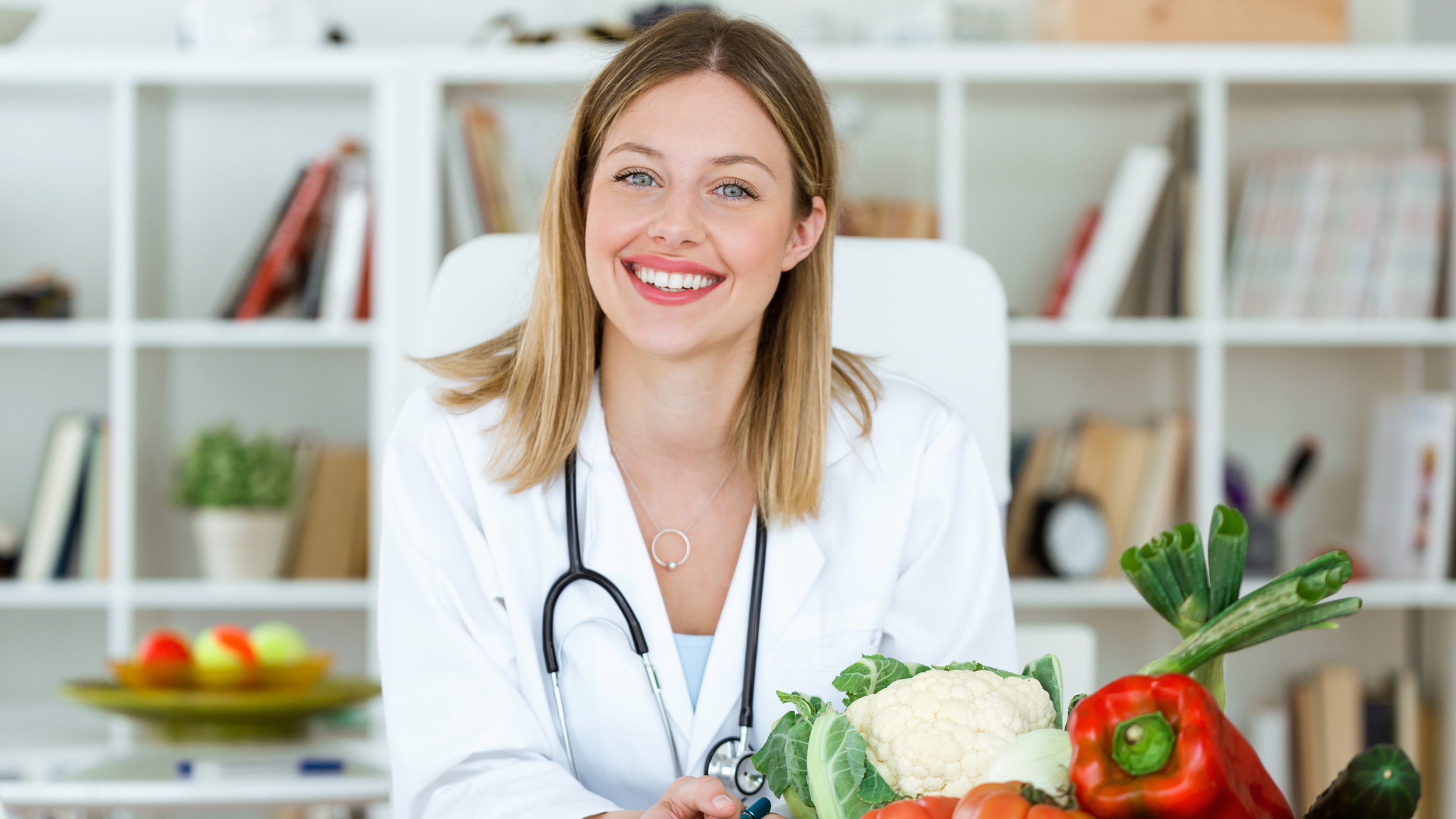 Ernährungsberaterin, blonde Frau mit blauen Augen, Gemüse auf dem Tisch