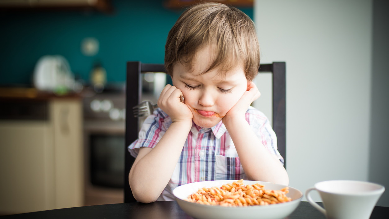 Kind sitzt vor Teller mit glutenfreien Nudeln
