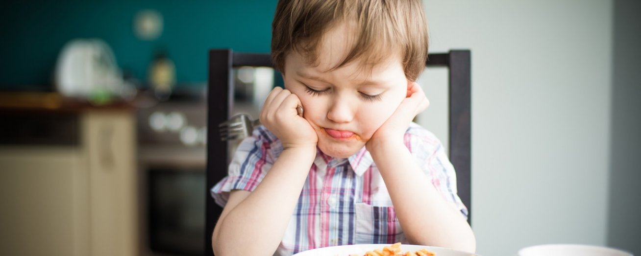 Kind sitzt vor Teller mit glutenfreien Nudeln