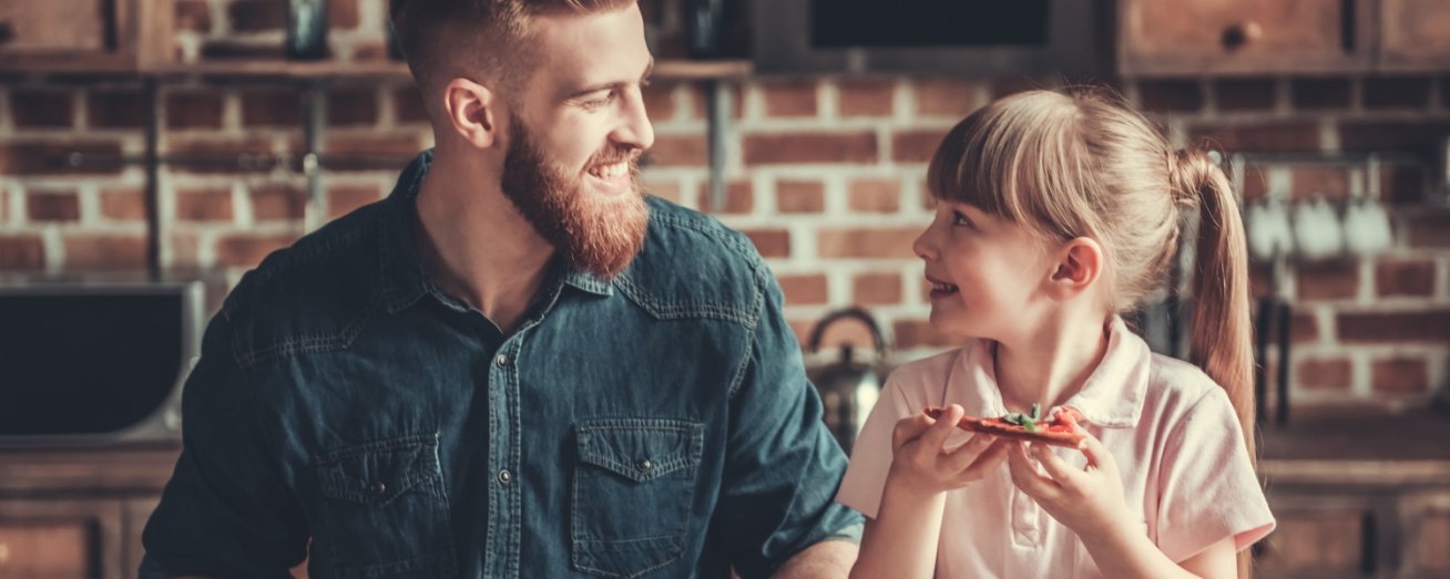 Kleines Mädchen isst etwas mit ihrem Vater